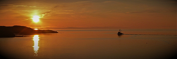 A fishing boat makes its way into the sunrise, across the Salish Sea. Photo by Alex Shapiro.